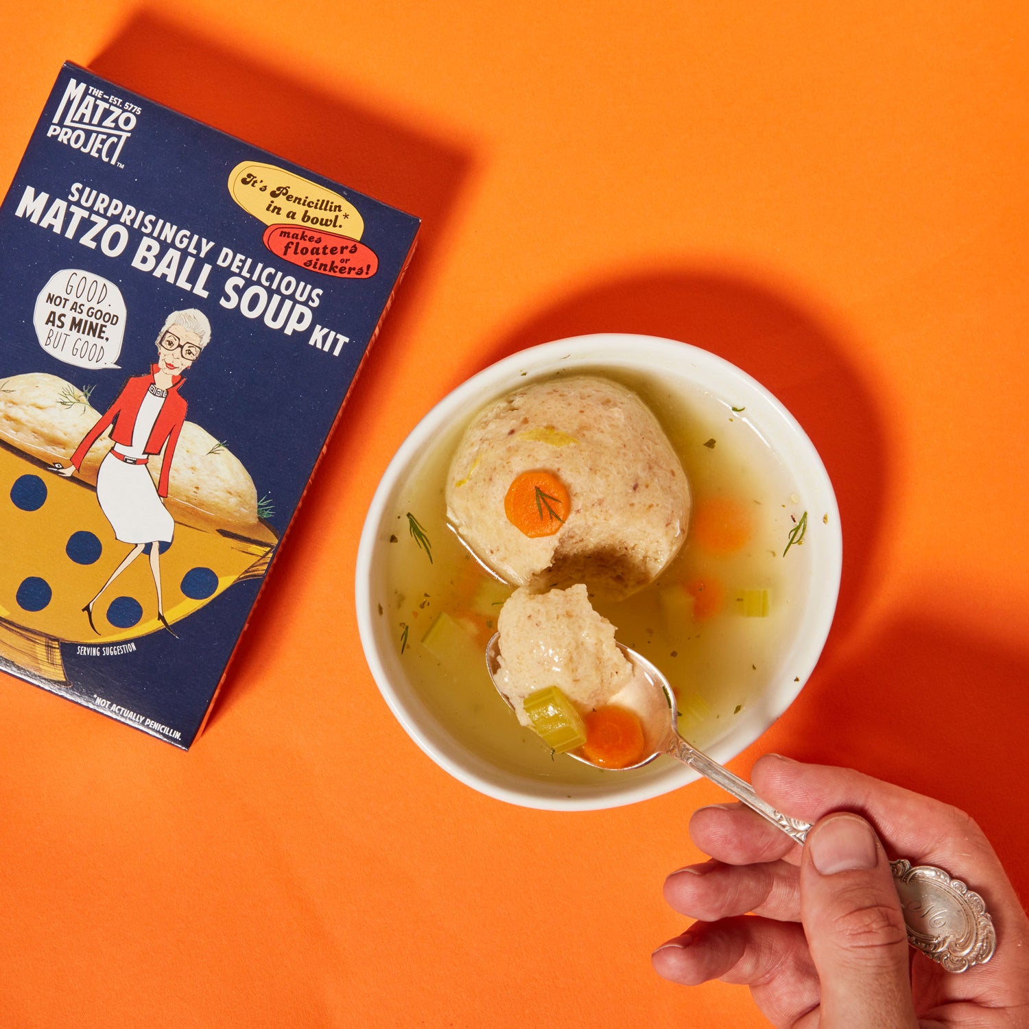 Hand using a spoon to dish out Matzo ball soup